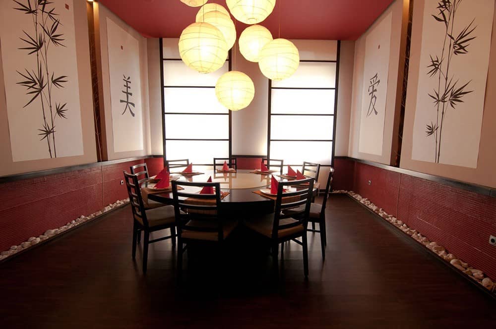 Interior restaurant chinezeasc cu mese rotunde și decor minimalist, iluminat cu lampi de hârtie.