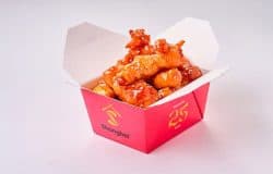 Pui caramelizat cu sos dulce și crocant, servit în cutie de carton roșie.