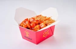 Pui dulce-acrișor cu legume și tăiței, servit în ambalaj de carton roșu.