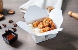 Imagine cu pui prajit Shanghai servit cu orez in cutie de carton.